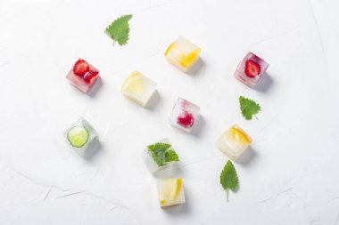 Beyaz taş arka planda meyve ve nane yaprakları ile buz küpleri