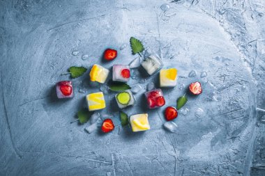 Taş mavi arka planda meyve ve kırık buz ile buz küpleri. 