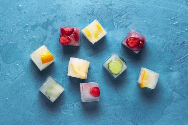 Taş mavi arka planda meyve ile buz küpleri. Nane, çilek