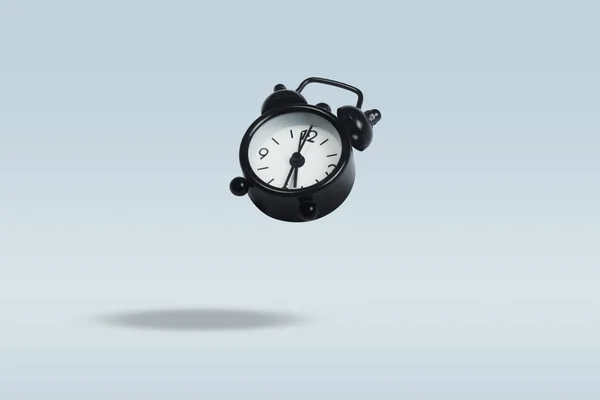 青い背景に黒の目覚まし時計をフライング。浮上。Conce — ストック写真