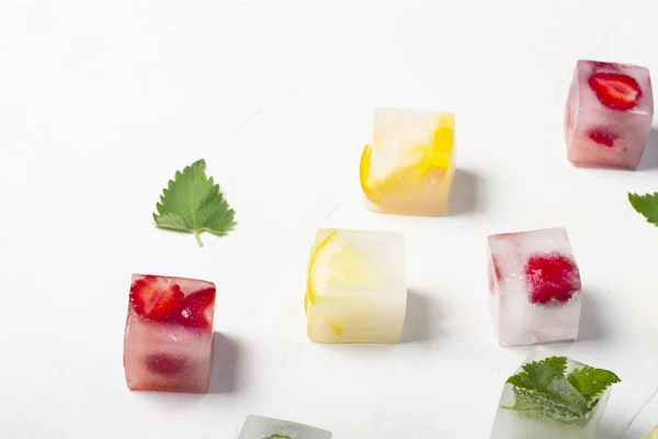 Ледяные кубики с фруктами и мятными листьями на белом фоне — стоковое фото