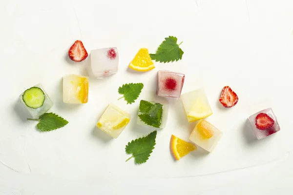 Ледяные кубики с фруктами и мятными листьями на белом фоне — стоковое фото