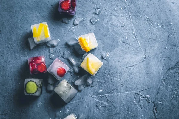 Eiswürfel mit Früchten und Eisbrocken auf steinblauem Hintergrund. — Stockfoto