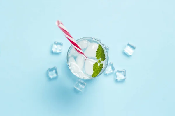 Glas koud en verfrissend water met ijs en munt op een blauwe b — Stockfoto