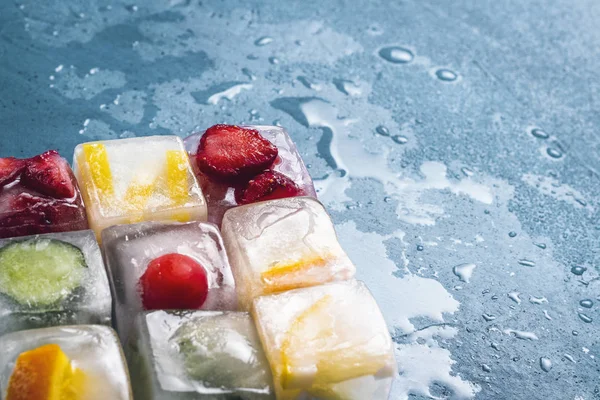 Ice cubes with fruit on a stone blue background. The shape of th — Stock Photo, Image