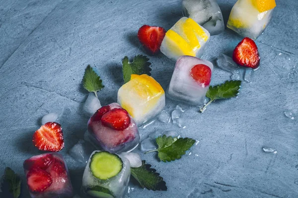 Ice cubes with fruit and broken ice on a stone blue background w — Stock Photo, Image