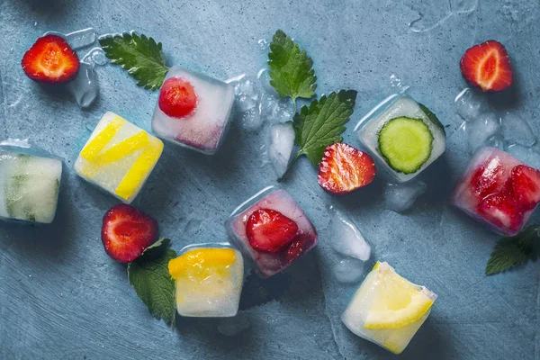 Ice cubes with fruit and broken ice on a stone blue background w — Stock Photo, Image