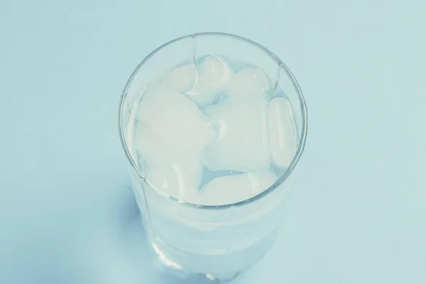 Refreshing cold Water with ice in a glass on a blue background. — Stock Photo, Image