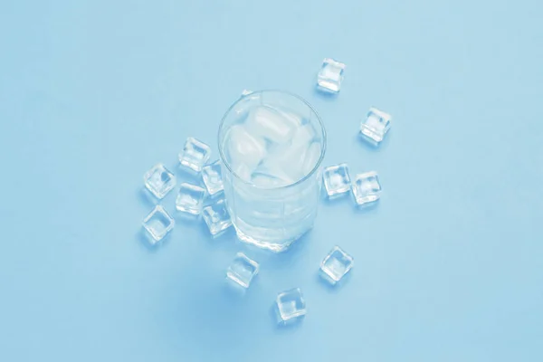 Glas erfrischend kaltes Wasser mit Eis und Eiswürfeln auf blauem Grund — Stockfoto