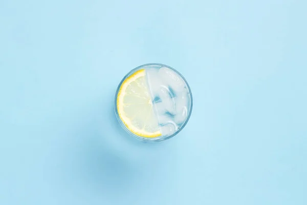 Vaso de agua o bebida con hielo y limón sobre fondo azul . — Foto de Stock