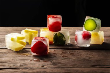 Ahşap arka plan üzerinde meyve ile buz küpleri. Sıcak yaz konsepti, tatlı