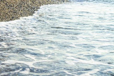 Şafak veya alacakaranlıkta çakıllı bir plajda deniz sörfü. Seascape. Dar odaklama