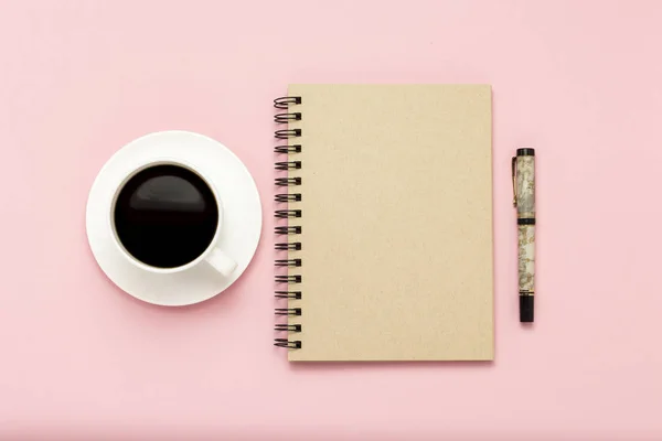 Weiße Tasse mit schwarzem Kaffee, Notizbuch, Stift auf rosa Hintergrund. — Stockfoto