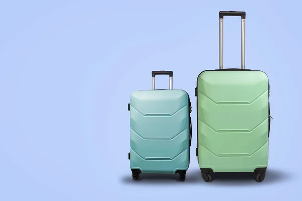 Két bőröndök a kerekek a kék háttérben. Az utazás fogalma — Stock Fotó