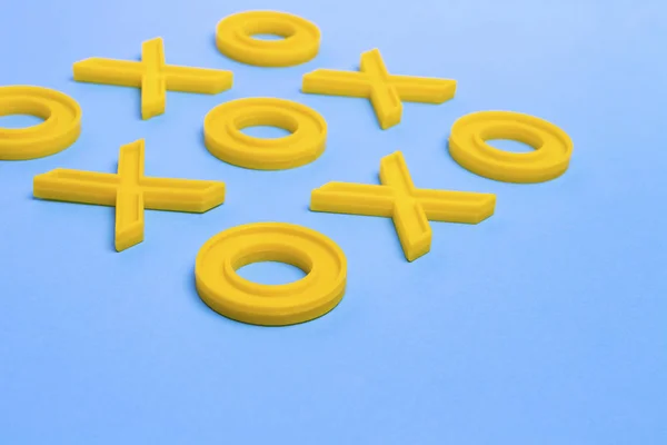 Yellow plastic crosses and zeroches for playing tic-tac-toe on a — Stock Photo, Image