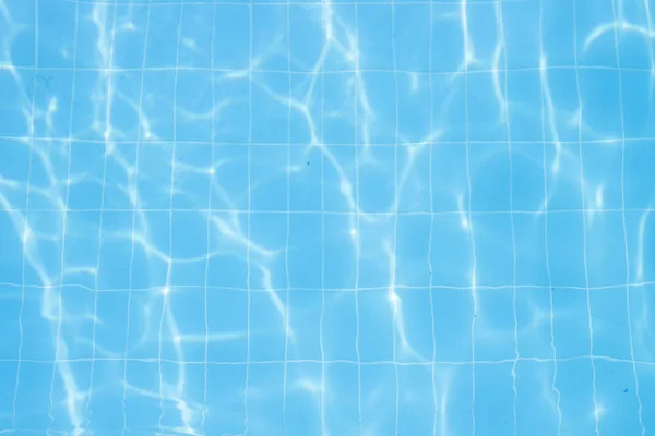 Water vibrations in the swimming pool with sun reflection. blue