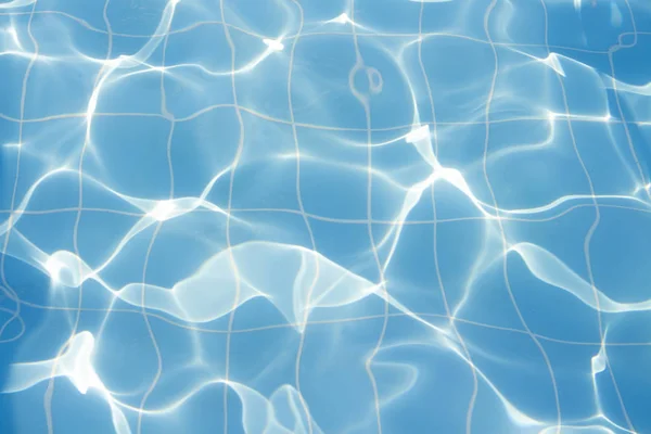 Water vibrations in the swimming pool with sun reflection. blue