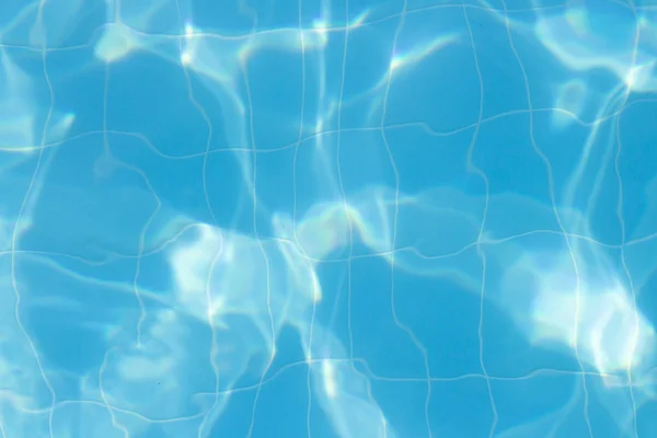 Water vibrations in the swimming pool with sun reflection. blue