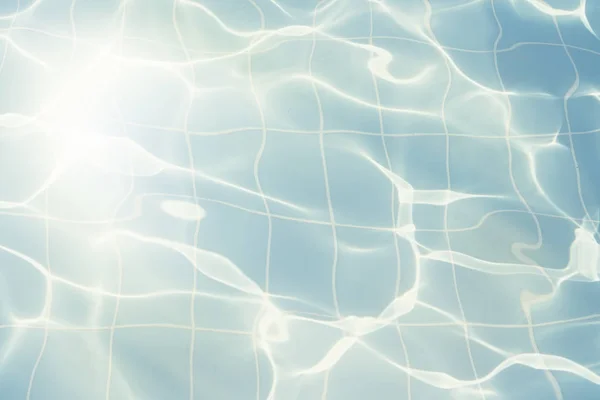 Water vibrations in the swimming pool with sun reflection. blue