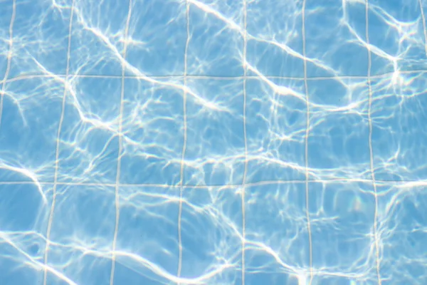 Water vibrations in the swimming pool with sun reflection. blue