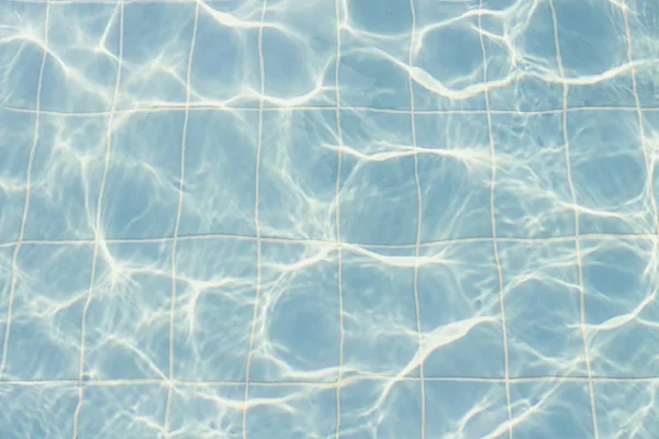 Water vibrations in the swimming pool with sun reflection. blue