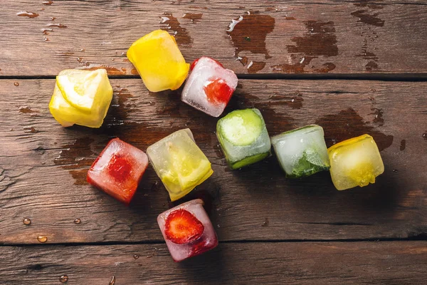 Cubos de gelo com frutas no fundo de madeira. O conceito de sobremesa quente de verão. Deitado plano, vista superior — Fotografia de Stock