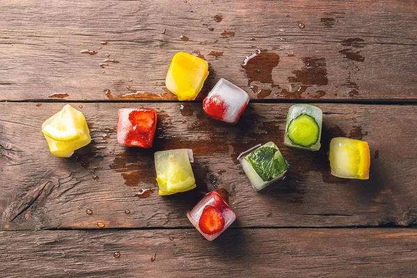 Cubos de gelo com frutas no fundo de madeira. O conceito de sobremesa quente de verão. Deitado plano, vista superior — Fotografia de Stock