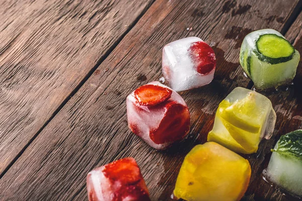 Ice cubes with fruit on wooden background. Hot summer concept, dessert — Stock Photo, Image