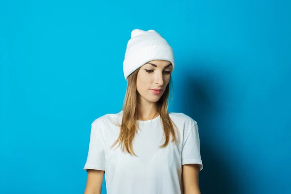 Jovem mulher de chapéu branco e camiseta em um fundo azul — Fotografia de Stock