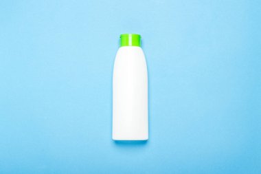 Mavi arka planda beyaz plastik şampuan şişesi. Düz döşeme, üst görünüm