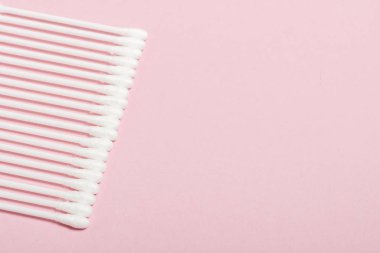 Pembe arka planda hijyenik pamuk tomurcukları. Kişisel bakım ürünleri kavramı. Düz döşeme, üst görünüm