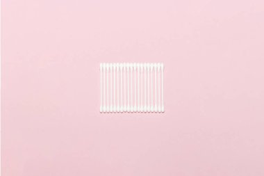 Pembe arka planda hijyenik pamuk tomurcukları. Kişisel bakım ürünleri kavramı. Düz döşeme, üst görünüm