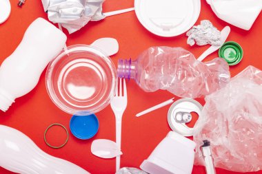Kırmızı arka planda plastik ve tin atık toplama. Kavram durdurmak plastik, geri dönüşüm, çöp ayrı toplama. Düz döşeme, üst görünüm