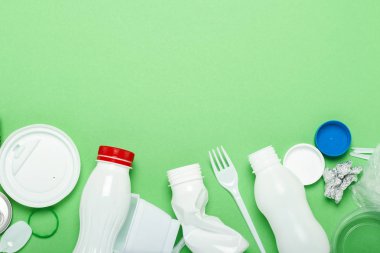 Çöp toplama, plastik ve metal yeşil bir arka plan üzerinde. Kavram durdurmak plastik, geri dönüşüm, çöp ayrı toplama. Düz döşeme, üst görünüm