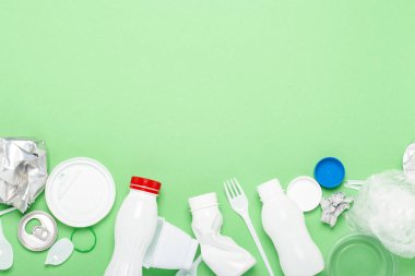 Çöp toplama, plastik ve metal yeşil bir arka plan üzerinde. Kavram durdurmak plastik, geri dönüşüm, çöp ayrı toplama. Düz döşeme, üst görünüm