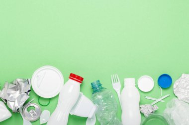 Çöp toplama, plastik ve metal yeşil bir arka plan üzerinde. Kavram durdurmak plastik, geri dönüşüm, çöp ayrı toplama. Düz döşeme, üst görünüm