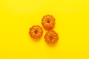 Sarı bir arka plan üzerinde dekoratif kabaklar. Cadılar Bayramı konsepti, hasat, sonbahar. Düz döşeme, üst görünüm