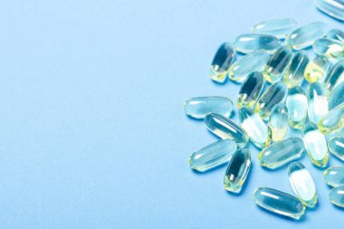 Mavi arka plandaki kapsüller. Vitamin kavramı, balık yağı, ilaç, ilaç, ilaç endüstrisi. Düz döşeme, üst görünüm