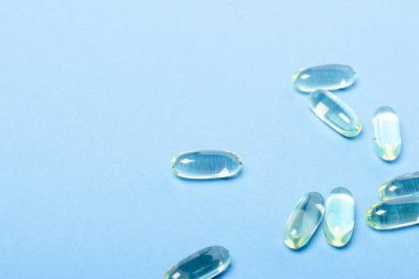 Mavi arka plandaki kapsüller. Vitamin kavramı, balık yağı, ilaç, ilaç, ilaç endüstrisi. Düz döşeme, üst görünüm