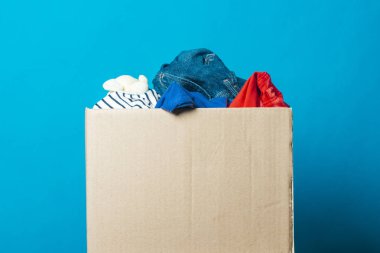 Mavi arka plan daki eşyaların olduğu karton kutu. Bağış kavramı