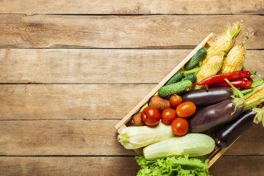 Ahşap bir arka plan üzerinde taze sebze ile ahşap kutu. İyi hasat konsepti, doğal ürün. Düz döşeme, üst görünüm