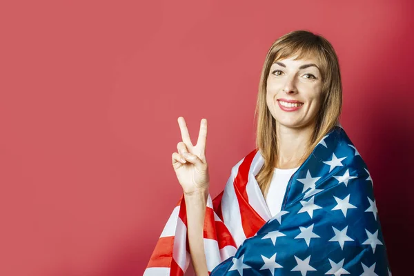 Young girl holds the US flag on a pink background. Concept patriot, holiday, independence day, memorial day, US visa, emigration to USA, education in USA