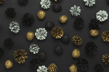 Çam kozalakları ve fındık siyah bir zemin üzerine altın, siyah, beyaz renklerde boyanmış. Desen. Mutlu yeni yıl ve mutlu Noeller kavramı. Düz yatıyordu, en iyi görünümü