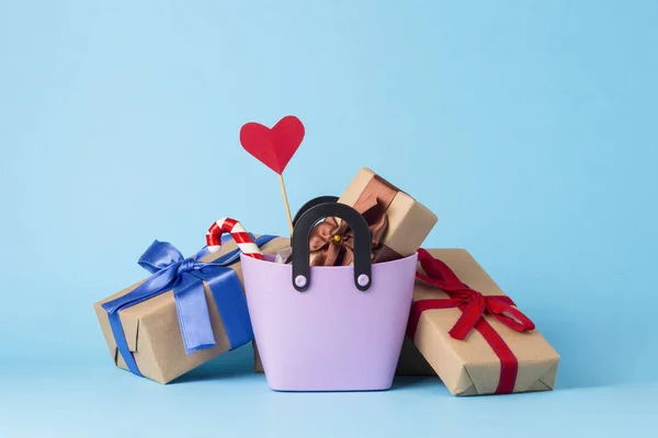Small plastic bag for shopping, gift boxes, heart on a stick, blue background. Concept of pre-holiday shopping, gifts for friends and relatives, Christmas sale, Valentine\'s Day