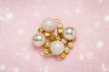 Noel ağacı süslemeleri, topları, kar ile açık pembe bir arka plan üzerinde çelenk. Mutlu Noeller ve Mutlu Yıllar konsepti. Düz döşeme, üst görünüm