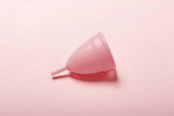 Cangkir menstruasi dengan latar belakang merah muda. Konsep menstruasi. Letak datar, atas — Stok Foto