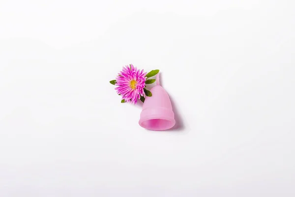 Pink menstruációs csésze és a virág fehér alapon. A menstruáció fogalma, a női higiéniai termékek közötti választás. Lapos feküdt, felső — Stock Fotó