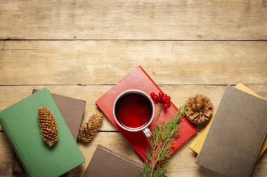 Kitaplar, çay ve külahlı metal bir bardak, ahşap arka planda bir Noel ağacı filizi. Sonbahar, kış, kır evinde tatil, kış tatili kavramı. Düz yatış, üst görünüm