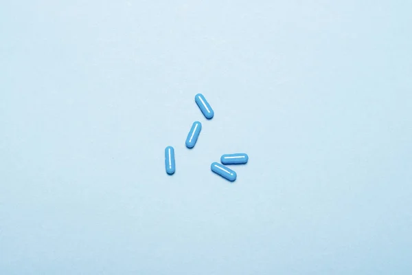 Cápsulas azuis com medicamento sobre fundo azul. Conceito de medicação, doença, droga, doente. Deitado plano, vista superior — Fotografia de Stock