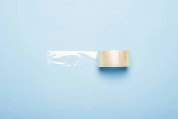 Transparent adhesive tape for packaging on a blue background. Flat lay, top view